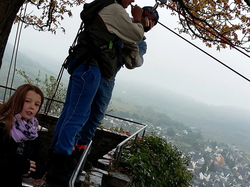 Person wird am Startpunkt der Seilrutsche gesichert.